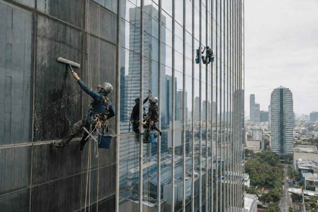 Rope-access technicians using professional equipment to clean a commercial tower’s exterior windows in Metro Manila